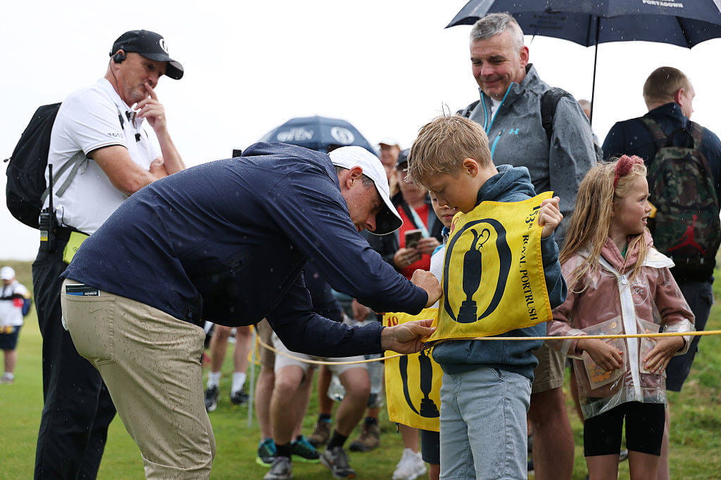 Rory McIlroy signs an autograph for a young fan at Royal Portrush ahead of The 153rd Open